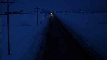 Movie still from “Affliction” (1997), directed by Paul Schrader – A car driving down a snowy road at night; Extreme Wide shot, High angle