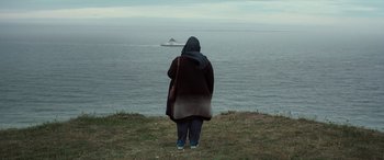 Movie still from “After Love” (2020), directed by Aleem Khan – A woman standing on a hill looking out at the ocean; Extreme Wide shot, Low angle