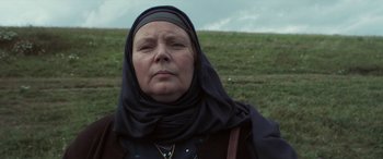 Movie still from “After Love” (2020), directed by Aleem Khan – An older woman wearing a headscarf in a grassy field; Close Up shot, Low angle
