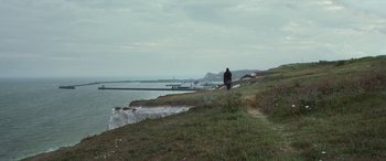 Movie still from “After Love” (2020), directed by Aleem Khan – A person standing on top of a grass covered hill; Extreme Wide shot, High angle