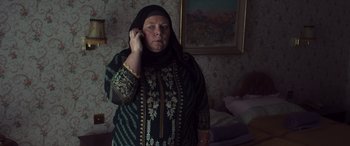 Movie still from “After Love” (2020), directed by Aleem Khan – An older woman wearing a headscarf talking on a cell phone; Medium shot, High angle