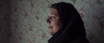 Movie still from “After Love” (2020), directed by Aleem Khan – An older woman wearing a head covering looking to her left; Close Up shot, Low angle