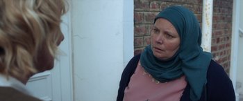 Movie still from “After Love” (2020), directed by Aleem Khan – An older woman wearing a head scarf and a pink shirt; Close Up shot, Over the shoulder angle