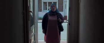 Movie still from “After Love” (2020), directed by Aleem Khan – A woman wearing a headscarf standing in a doorway; Medium shot, Low angle