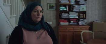 Movie still from “After Love” (2020), directed by Aleem Khan – A woman wearing a headscarf in front of a bookcase; Close Up shot, Over the shoulder angle