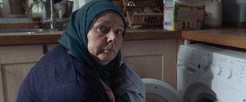 Movie still from “After Love” (2020), directed by Aleem Khan – An older woman wearing a head scarf in front of a toilet; Close Up shot, Over the shoulder angle