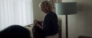 Movie still from “After Love” (2020), directed by Aleem Khan – A woman sitting on a chair holding a pair of scissors; Medium shot, Over the shoulder angle