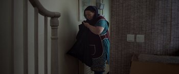 Movie still from “After Love” (2020), directed by Aleem Khan – A woman in a blue dress holding a black bag; Medium shot, Over the shoulder angle