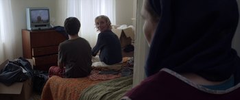Movie still from “After Love” (2020), directed by Aleem Khan – A woman sitting on top of a bed next to two other people; Medium shot, Over the shoulder angle
