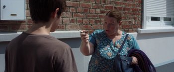 Movie still from “After Love” (2020), directed by Aleem Khan – A woman is holding a cigarette and talking to a man; Medium shot, Over the shoulder angle