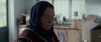 Movie still from “After Love” (2020), directed by Aleem Khan – A woman with a head covering in a kitchen; Close Up shot, Over the shoulder angle