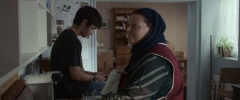 Movie still from “After Love” (2020), directed by Aleem Khan – An older woman and a young man are looking at a cell phone; Medium shot, Over the shoulder angle