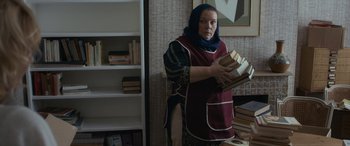 Movie still from “After Love” (2020), directed by Aleem Khan – A woman holding a stack of books in her hands; Medium shot, Low angle