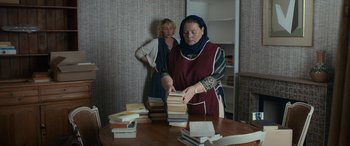 Movie still from “After Love” (2020), directed by Aleem Khan – Two women standing in front of a stack of books on a table; Medium shot, Over the shoulder angle