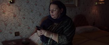 Movie still from “After Love” (2020), directed by Aleem Khan – An older woman looking at her cell phone; Close Up shot, Low angle
