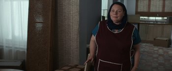 Movie still from “After Love” (2020), directed by Aleem Khan – A woman standing in front of a table with boxes; Medium shot, Over the shoulder angle