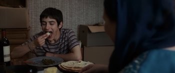 Movie still from “After Love” (2020), directed by Aleem Khan – A man sitting at a table with a plate of tortillas; Medium shot, Over the shoulder angle