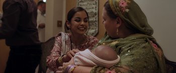 Movie still from “After Love” (2020), directed by Aleem Khan – Two women are holding a baby and smiling at each other; Medium shot, Over the shoulder angle