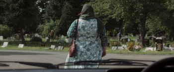 Movie still from “After Love” (2020), directed by Aleem Khan – A woman in a floral dress walking down the street; Wide shot, Over the shoulder angle
