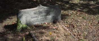 Movie still from “After Love” (2020), directed by Aleem Khan – A grave marker in the middle of a field; Wide shot, Overhead angle