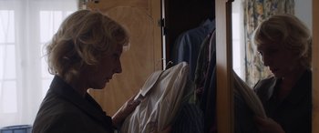 Movie still from “After Love” (2020), directed by Aleem Khan – A woman looking at a suit jacket in a closet; Close Up shot, Over the shoulder angle