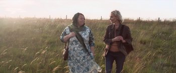 Movie still from “After Love” (2020), directed by Aleem Khan – Two women are walking through a field of tall grass; Medium shot, Over the shoulder angle
