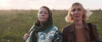 Movie still from “After Love” (2020), directed by Aleem Khan – Two women standing in a grassy field with one wearing a scarf; Close Up shot, Low angle
