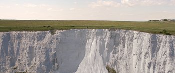 Movie still from “After Love” (2020), directed by Aleem Khan – A man standing on a cliff looking over a grassy field; Extreme Wide shot, High angle