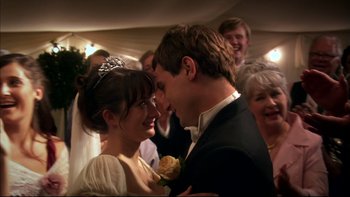 Movie still from “After the Wedding” (2006), directed by Susanne Bier – A man and a woman in formal wear standing next to each other in front of a group of people; Close Up shot, Over the shoulder angle