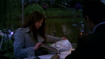 Movie still from “After the Wedding” (2006), directed by Susanne Bier – A woman sitting at a table with a glass of wine; Medium shot, Over the shoulder angle