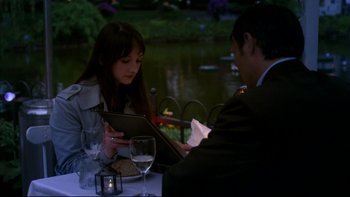Movie still from “After the Wedding” (2006), directed by Susanne Bier – A man and a woman sitting at a table with a glass of wine; Medium shot, Over the shoulder angle