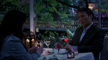 Movie still from “After the Wedding” (2006), directed by Susanne Bier – Two people sitting at a table with wine glasses and food; Medium shot, Over the shoulder angle