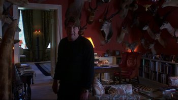 Movie still from “After the Wedding” (2006), directed by Susanne Bier – A man standing in front of a wall of taxidermied animals; Medium shot, Over the shoulder angle