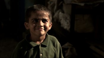 Movie still from “After the Wedding” (2006), directed by Susanne Bier – A young boy in a green shirt is smiling for the camera; Close Up shot, High angle