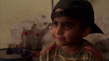 Movie still from “After the Wedding” (2006), directed by Susanne Bier – A young boy wearing a hat and a striped shirt; Close Up shot, High angle
