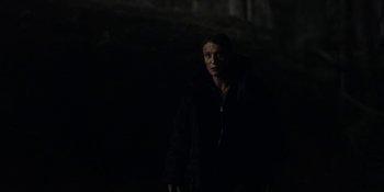 Movie still from “Dark” (2017), created by Baran bo Odar – A man standing in the dark in a dark room; Medium shot, Low angle
