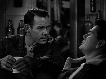 Movie still from “Air Force” (1943), directed by Howard Hawks – A man and a woman sitting next to each other in a room; Close Up shot, Over the shoulder angle