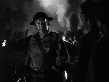 Movie still from “Air Force” (1943), directed by Howard Hawks – An old man in a hat and a man in an army uniform stand in front of a burning building; Medium shot, Over the shoulder angle