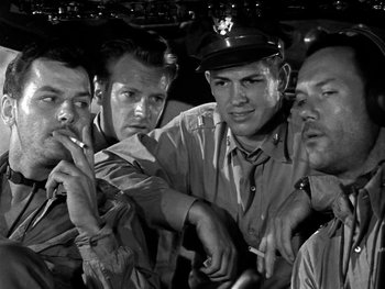 Movie still from “Air Force” (1943), directed by Howard Hawks – A black and white photo of a group of men smoking cigarettes; Close Up shot, Low angle
