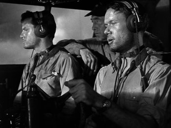 Movie still from “Air Force” (1943), directed by Howard Hawks – A group of men wearing headphones in a room; Medium shot, Low angle