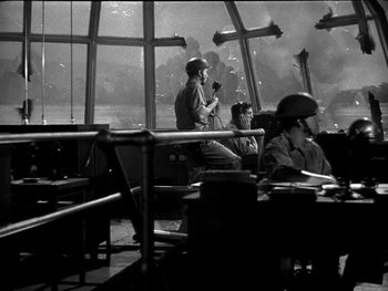 Movie still from “Air Force” (1943), directed by Howard Hawks – Two men sitting at a table in front of a window; Wide shot, Low angle