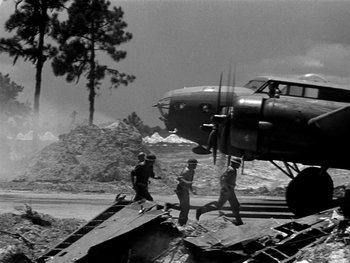 Movie still from “Air Force” (1943), directed by Howard Hawks – Three men are walking towards an airplane on the ground; Extreme Wide shot, Low angle