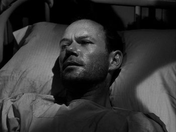 Movie still from “Air Force” (1943), directed by Howard Hawks – A black and white photo of a man laying in a bed; Close Up shot, High angle