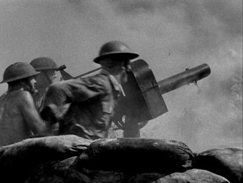 Movie still from “Air Force” (1943), directed by Howard Hawks – Two men in military uniforms are holding a gun; Medium shot, Low angle