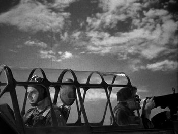 Movie still from “Air Force” (1943), directed by Howard Hawks – A black - and - white photo of two men looking out a window; Wide shot, Low angle