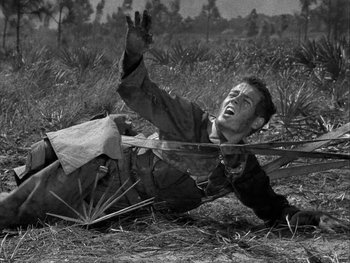 Movie still from “Air Force” (1943), directed by Howard Hawks – A man falling off his bike in the grass; Medium shot, Low angle