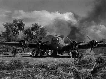 Movie still from “Air Force” (1943), directed by Howard Hawks – An airplane is parked on the ground near a forest; Extreme Wide shot, Low angle
