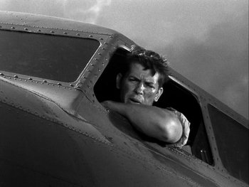 Movie still from “Air Force” (1943), directed by Howard Hawks – A black and white photo of a man looking out of an airplane window; Medium shot, Low angle