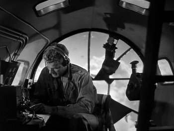 Movie still from “Air Force” (1943), directed by Howard Hawks – A man working on a computer inside a plane; Medium shot, Low angle