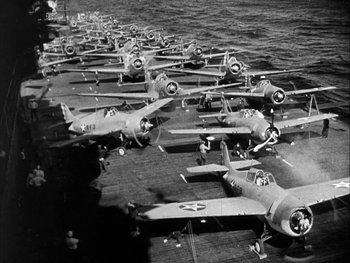 Movie still from “Air Force” (1943), directed by Howard Hawks – A group of fighter jets sitting on top of an aircraft carrier; Wide shot, High angle